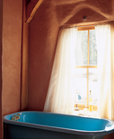 
Sheer curtains offer privacy while allowing natural light over the salvaged tub. Paula loves to look out over the meadow while she relaxes in the bathtub.
